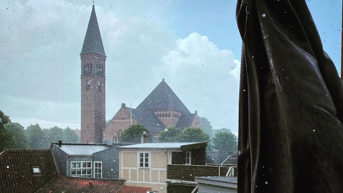 En kirke med tårn og en mørk paraply i forgrunden