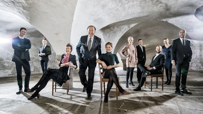 En gruppe formelt klædte personer i et kælderlignende rum