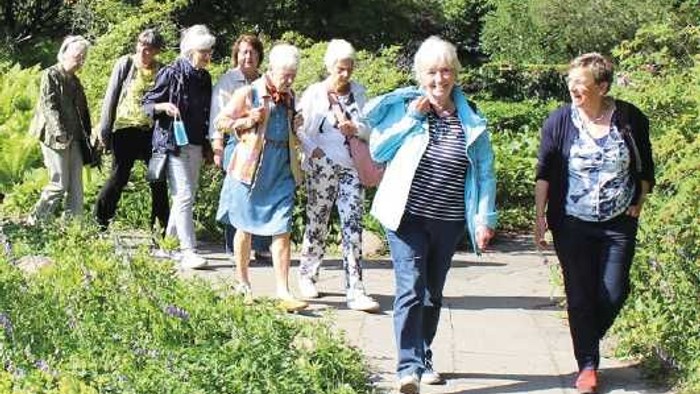 Eine Gruppe älterer Menschen spaziert in einem Garten.