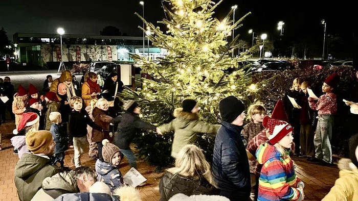 En menneskemængde samlet omkring et stort juletræ om natten.