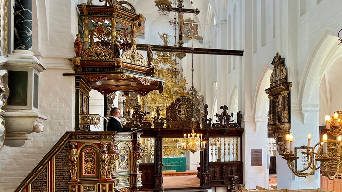 Indre del af en prægtig kirke med gulddekorerede alter og hængende kandeler