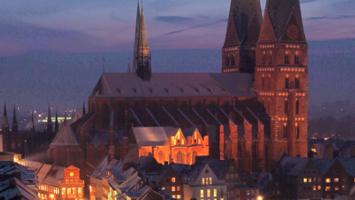 Großes, beleuchtetes Kirchengebäude bei Dämmerung in Schneelandschaft