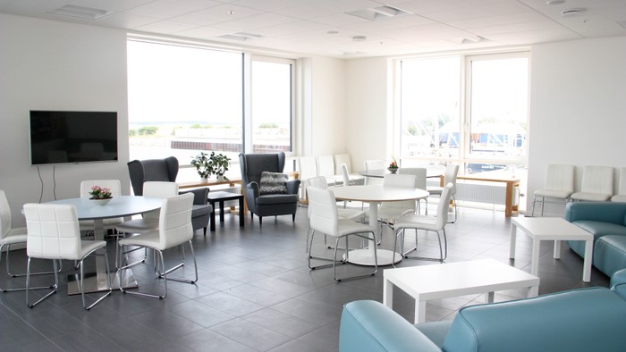 Et moderne kontor med hvide bord, blå stole og store vinduer