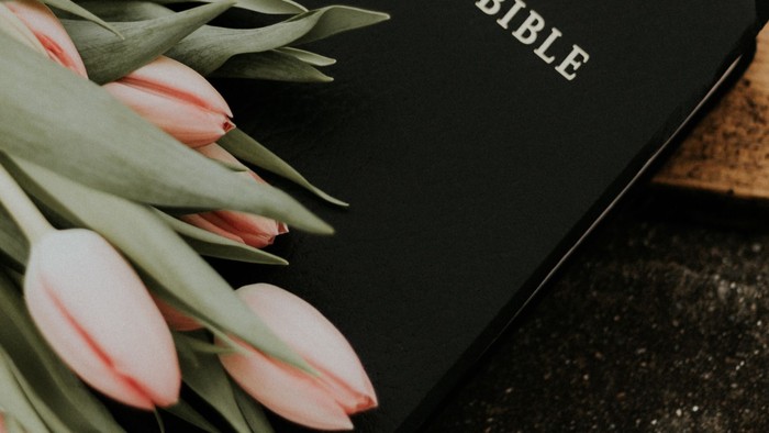 En blomsterstrå til tulipaner ved siden af en håndskrevet bibel.