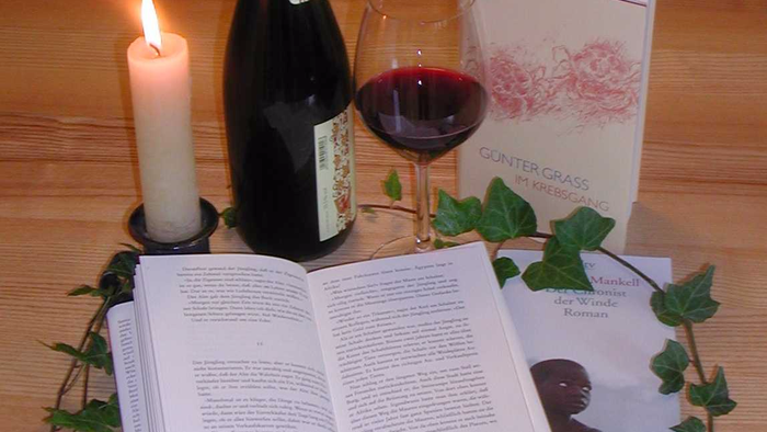 Wein, Kerze und Buch auf Holztisch