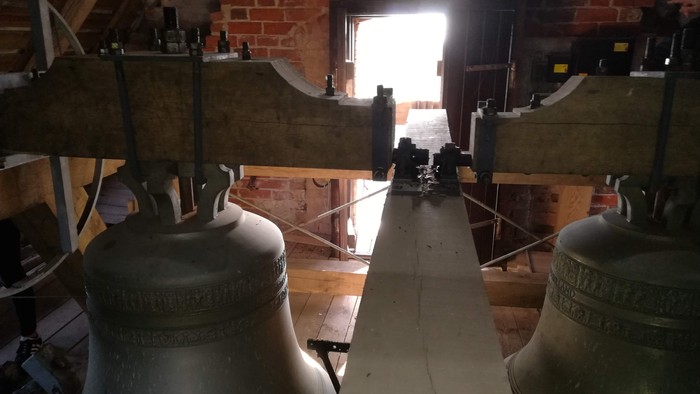 To bjergklokker i et tårn med mursten og trækonstruktioner