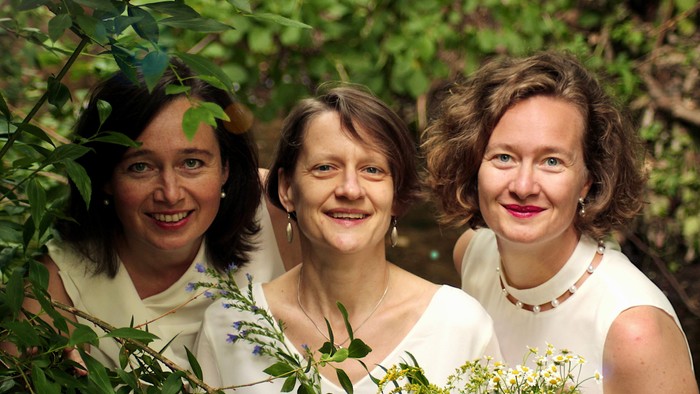 Drei Frauen lächeln in einem Garten