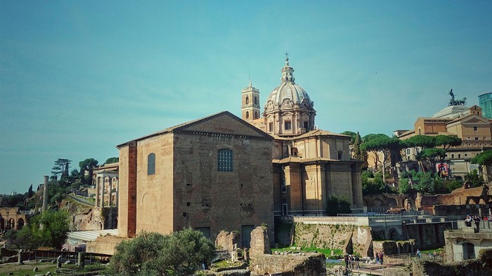 Das Bild zeigt eine historische Kirche mit Kuppel inmitten antiker Ruinen.