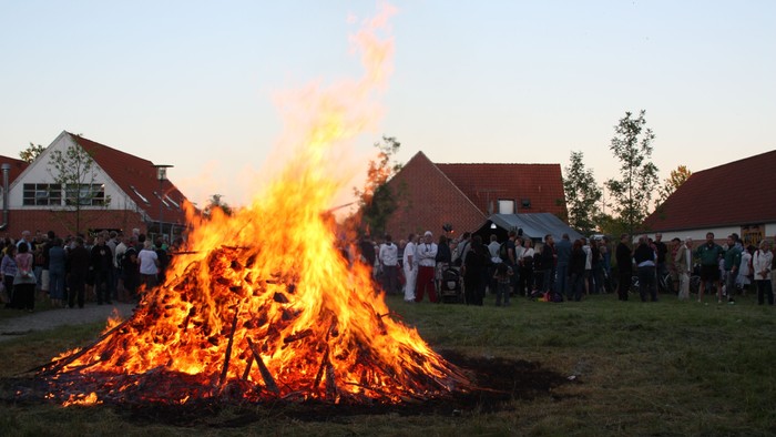 En stor bonfire med en folkemængde omkring, der ser på.