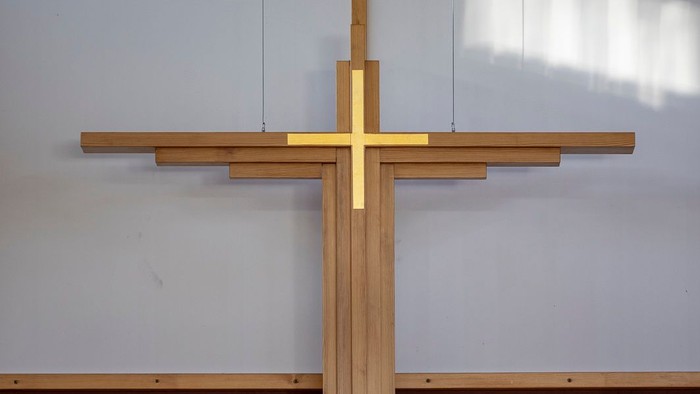 En stor, gul korsformet pryd på en hvide mur med et vindue ovenfor