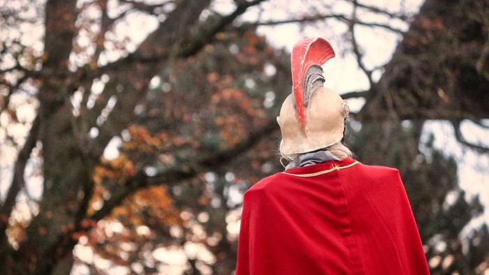 Person in rotem Umhang steht vor Bäumen