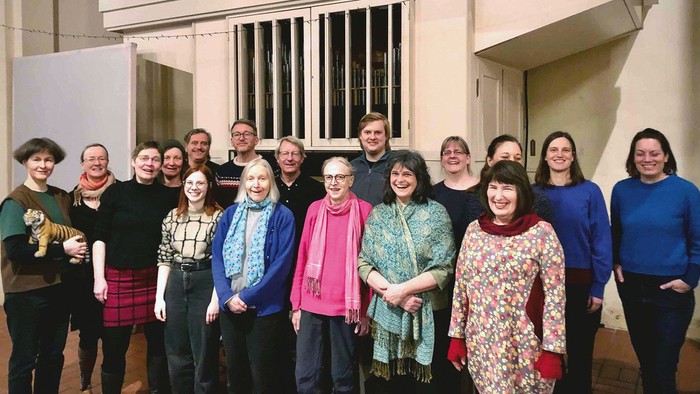 Eine Gruppe von Menschen posiert vor einem Gebäude mit Balkon und Treppe.
