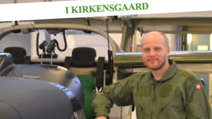 Mand i militæruniform står ved fly i museum.