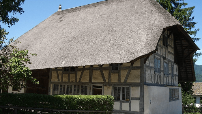 Das Bild zeigt ein traditionelles Fachwerkhaus mit Reetdach und gepflegtem Garten.