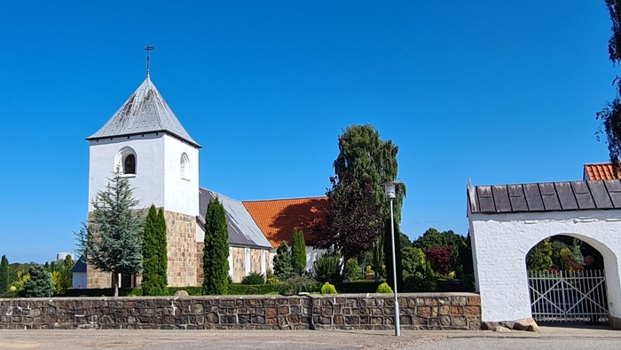 En kirke med tårn og en dansk flag på en klar dag