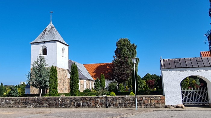 En kirke med tårn og en dansk flag på en klar dag