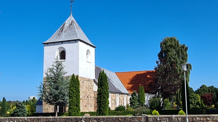 En kirke med tårn og en dansk flag på en klar dag