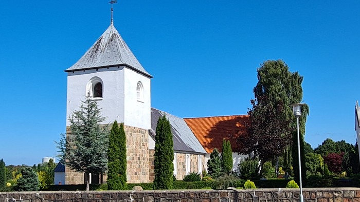 En kirke med tårn og en dansk flag på en klar dag