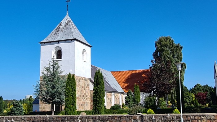 En kirke med tårn og en dansk flag på en klar dag