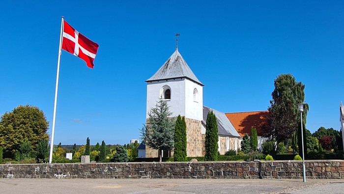 En kirke med tårn og en dansk flag på en klar dag