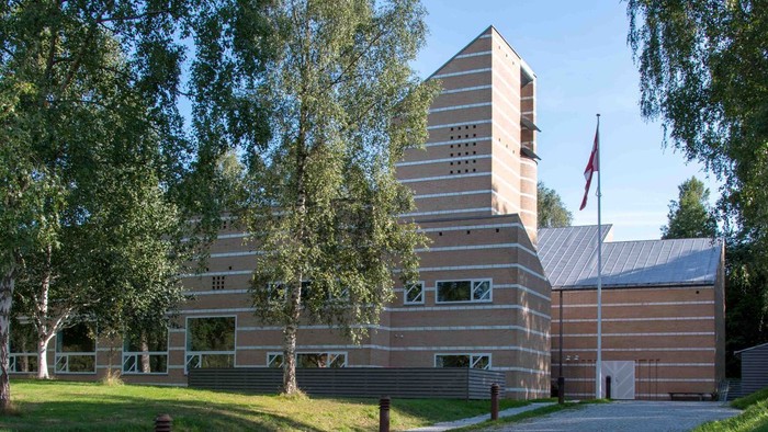 Et moderne bygning med træpanel og flagstang foran