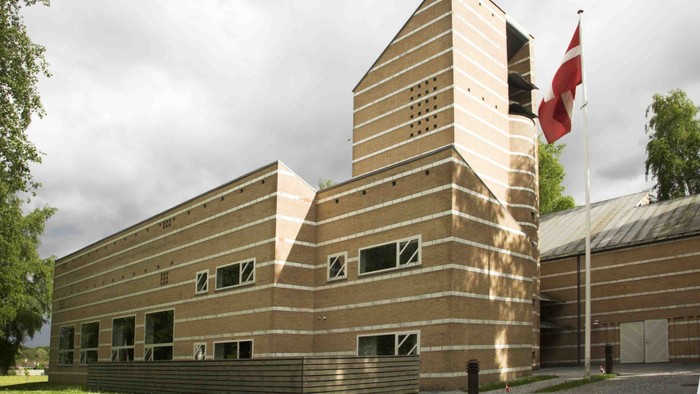 Bygningen er lavet af træ og har en moderne, geometrisk form.