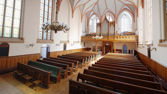 Innenraum einer Kirche mit Holzpulten und Orgel