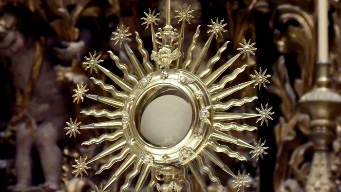 Golden monstrance with cross, likely in a church setting