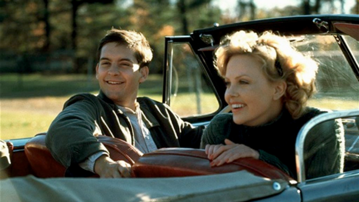 En mand og en kvinde sitter i et klassisk bil, begge smiler og ser lykkelig ud.