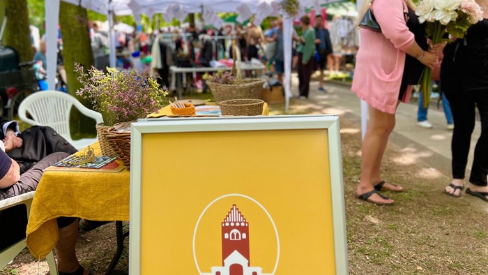 En markedsplads med mange stender og folk der køber blomster og andre varer