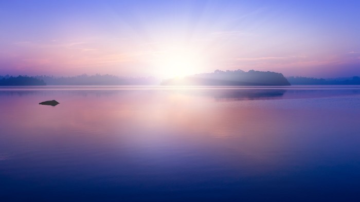 En rolig sø med solopgang og refleksioner
