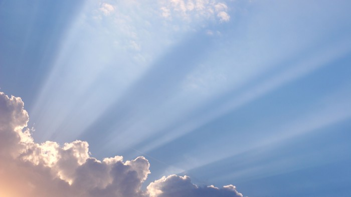 Solstråler gennem skyer i blå himmel