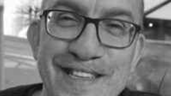 En smilende mand med briller og kort hår.