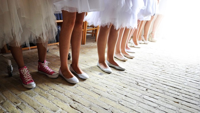 En rekke danser i balettstøvler og strømper, en med rosa sneakers.