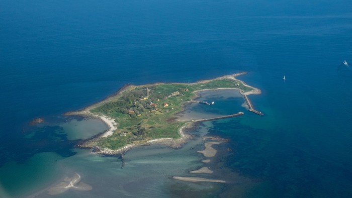 En lille ø i havet med en lille bugt og sandstrand.