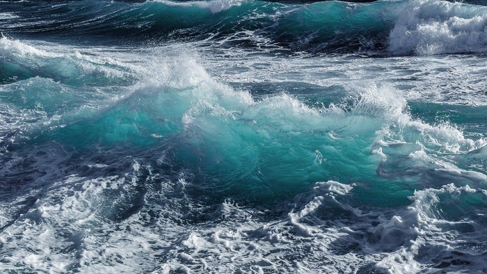 Türkisfarbene Wellen brechen wild am Meer.