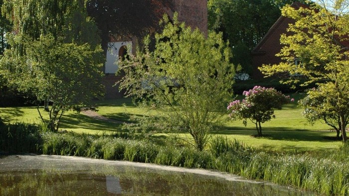 En rolig park med en lille sø og et historisk tårn i baggrunden