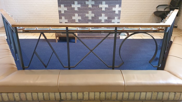 En blå balustrade med sort jernarbejde foran en hvid køkkenbord med sorte og hvide tæpper.