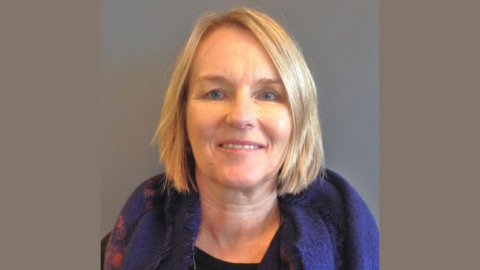 En kvinde med kort blond hår og en blå jakke.