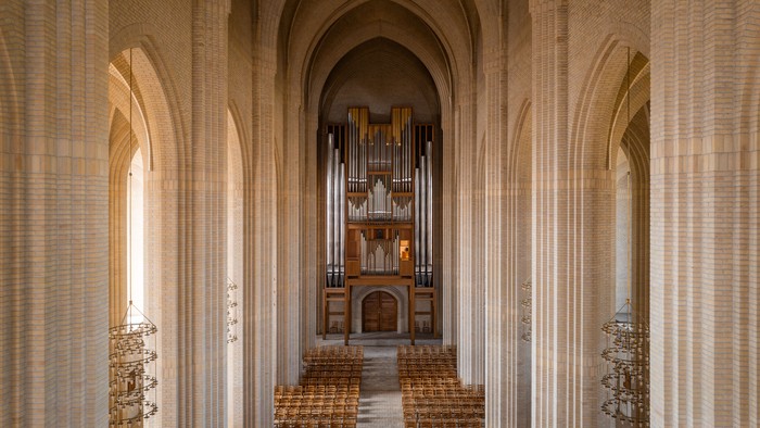 Indre del af en stor kirke med orgel og træbænke.