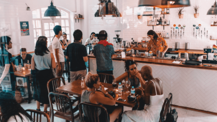 Ein gemütliches Café mit vielen Gästen, die an Tischen sitzen und sich unterhalten.