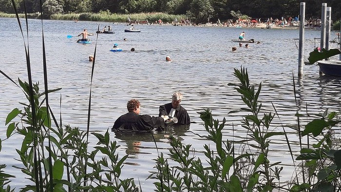 Menschen genießen den Tag am See, einige schwimmen und liegen auf Luftmatratzen.