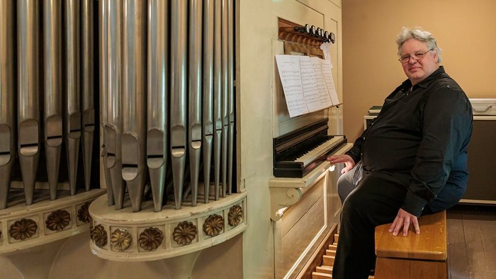 Mann spielt Klavier vor großem Orgelpfeifenwerk