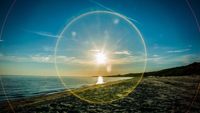 En solopgang over stranden med en lille båd i vandet
