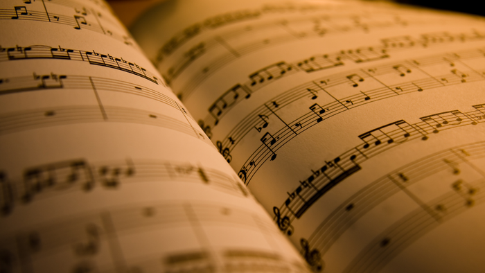 Et nært billede af noter på en blækspridt musikbogen