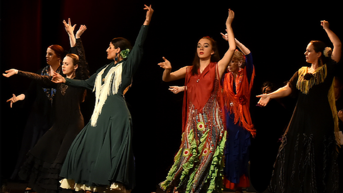 Tänzerinnen in bunten Kleidern performen auf Bühne