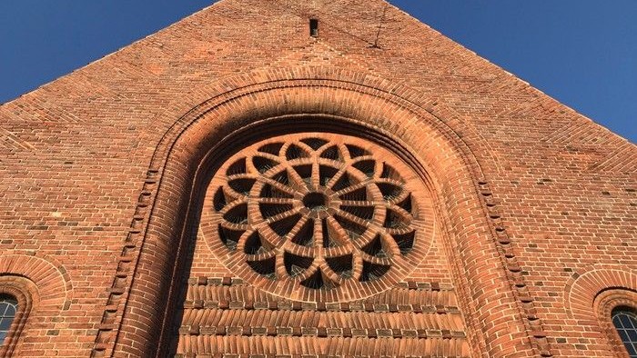 Røde mursten med indgraveret rosette-mønster i mursten over indgang.