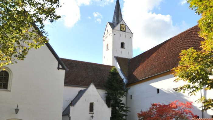 En hvid kirke med tårn og træer med faldne blade.