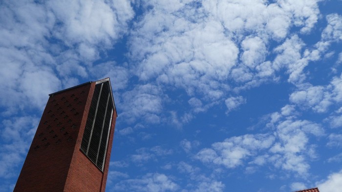 En høj rød murstenstorn med skyer og blå himmel