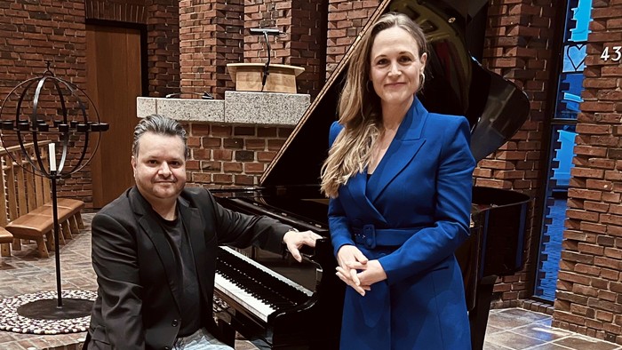 En mand og en kvinde ved et piano i et rødmuret rum
